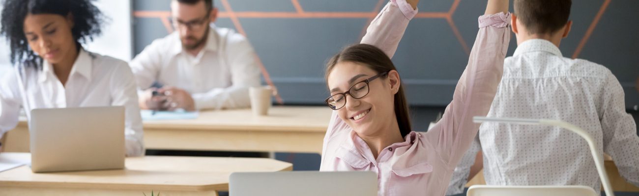 Millennial employee taking break from computer, young businesswoman or student stretching at workplace in multiracial coworking, relaxed manager happy to finish work enjoying pause for relaxation